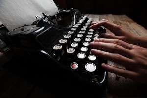 Hands writing on old typewriter over wooden table background